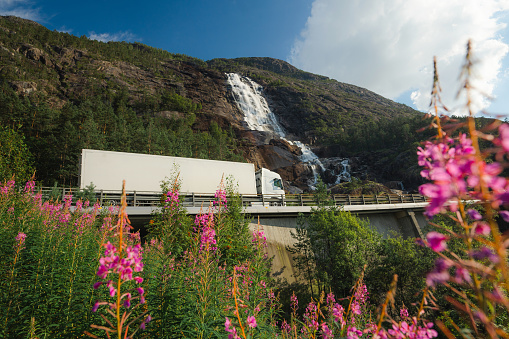 Scenic view of  truck on the road near  the waterfall that falls into fjord in Norway