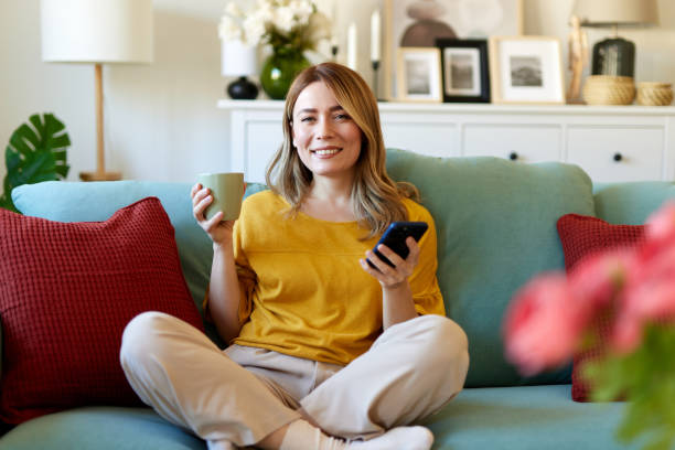 istock Woman using smartphone while drinking coffee at her home in the morning 1487521283