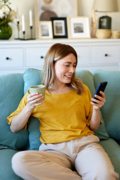 istock Woman using smartphone while drinking coffee at her home in the morning 1487521329