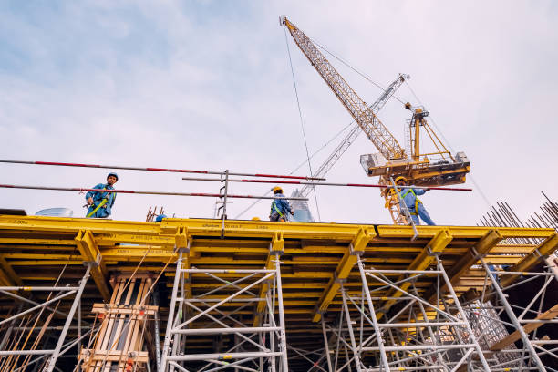 Workers in helmets on a construction site with crane machinery stock photo