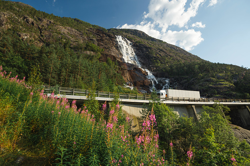 Scenic view of  truck on the road near  the waterfall that falls into fjord in Norway