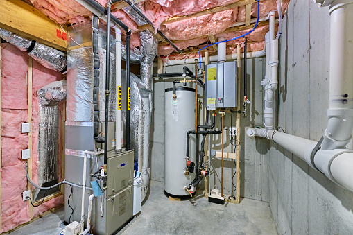 Unfinished basement mechanical room with tankless water heater, storage tank, plumbing and heating systems