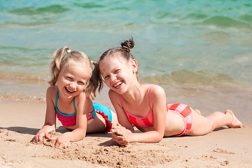 Happy Children Tanning Lying Enjoying on Sandy Beach. Kids Have fun Summer Holiday.
