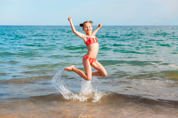 istock Happy Child Jumping on Beach on Sea Waves Background 1487525112