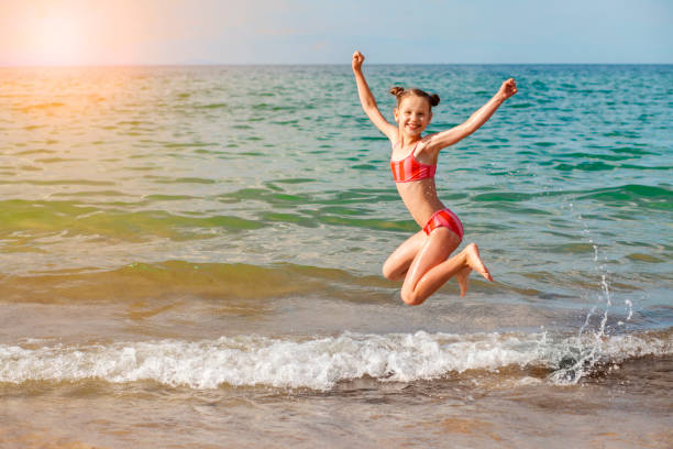 istock Jumping Girl Child Having fun on Sea Beach 1487525116