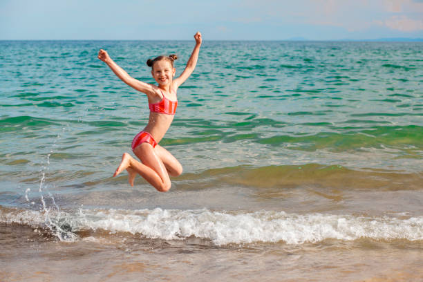 istock Happy Child Jumping on Beach on Sea Waves 1487525117