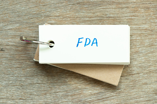 Flash card with handwriting word FDA (abbreviation of food and drug administration) on wood background