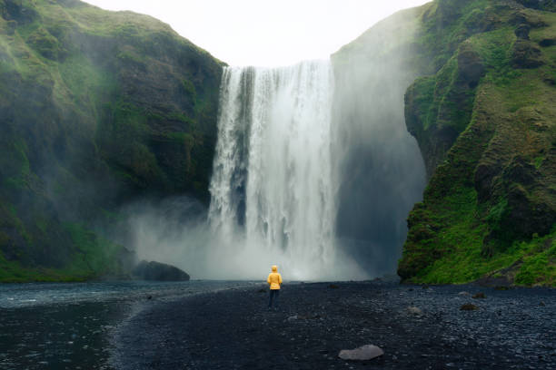 cachoeira de skogafoss fluindo com mulher asiática em pé no verão na islândia - scenics landscape nature the natural world - fotografias e filmes do acervo