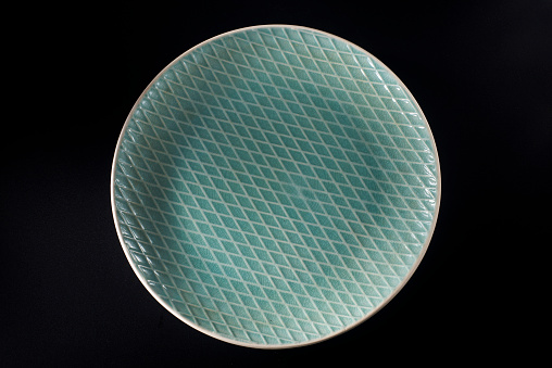 A dark green ceramic plate with a diamond-shaped cross-line stripe