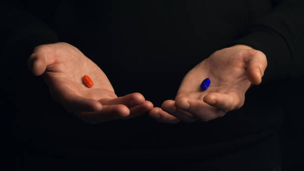 istock Studio shot hands show red pill and blue pill isolated on black background. Concept of making right choice. 1487534507