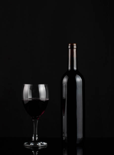 istock Red wine bottle and glass on dark background 1487537375