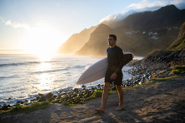 istock Surfer walking on a beautiful beach at sunrise. 1487540385