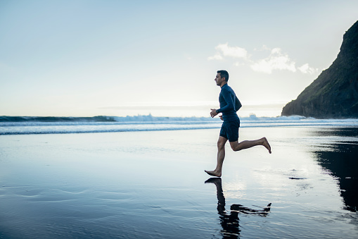 Man jogging on the beach and managing healthy lifestyle.