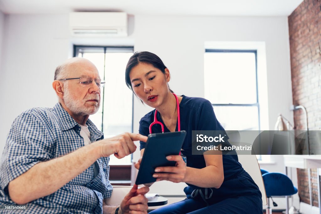 Nurse and her patient checking medical exams on a tablet and signing privacy agreement Nurse and her patient checking medical exams on a tablet and signing privacy agreement. Patient Stock Photo