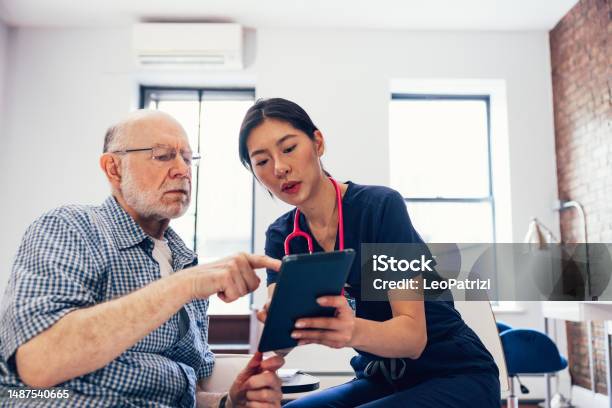 Nurse And Her Patient Checking Medical Exams On A Tablet And Signing Privacy Agreement Stock Photo - Download Image Now