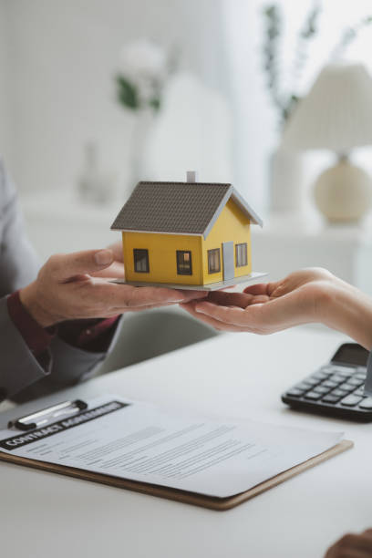 istock Real estate agents explain models of housing estates in projects to elaborate to clients, explaining and presenting information about homes and purchasing loans. Real estate trading concept. 1487542013