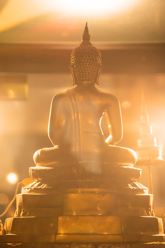 Back of Buddha statue with effect of orange lighting