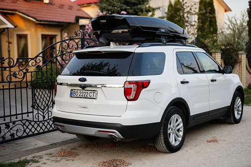 Ternopil, Ukraine -May, 2023: Ford Exlorer family car with roof rack Thule Motion XXL box in ukrainian license plates.