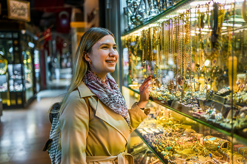 Young cheerful tourist woman looking at a jewelry store window in Grand Bazaar, Istanbul, Turkey