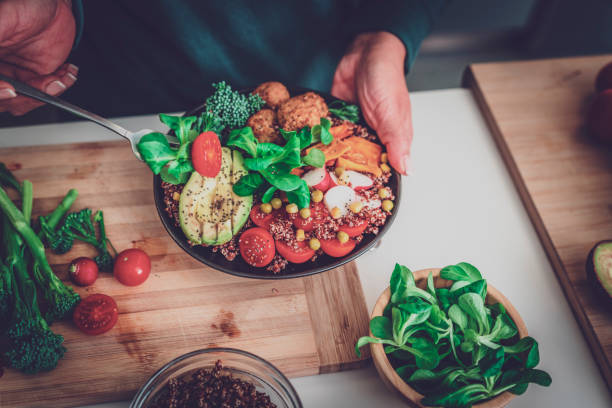 Close up of woman's hands holding a healthy plant-based salad plate and a fork. Healthy eating concept. High resolution 42Mp indoors digital capture taken with SONY A7rII and Zeiss Batis 40mm F2.0 CF lens