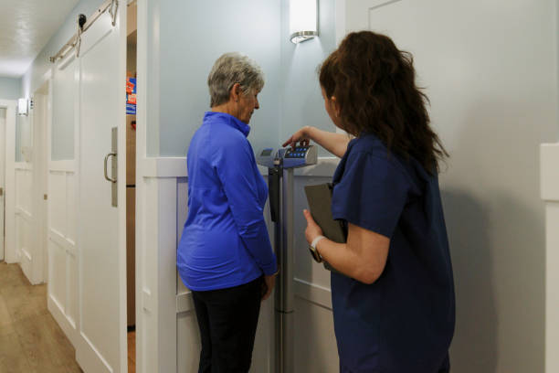 nurse in a doctor's office weighing a senior patient - dieting weight scale doctor patient imagens e fotografias de stock