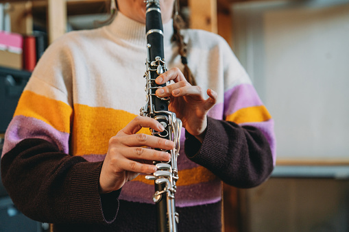 Detail of the hands of a clarinet player. The woman is playing clarinet to practice.