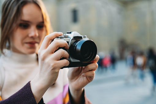 A woman is photographing the city at sunset. Close up shot of a woman using a camera.
