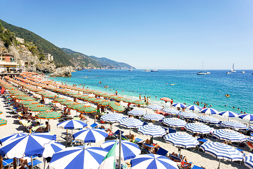 One of the beaches of Monterosso al Mare with some umbrellas and deck chairs with blue and white stripes
