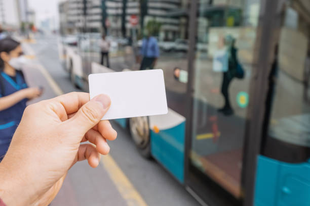 cartão de crédito ou transporte pré-pago na mão do passageiro contra o fundo de um ônibus urbano moderno na rua da cidade - prepaid card - fotografias e filmes do acervo