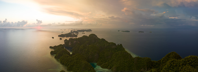 Sunrise illuminates dramatic limestone islands that rise from Raja Ampat's beautiful seascape. This remote part of Indonesia is known for its incredible marine biodiversity.