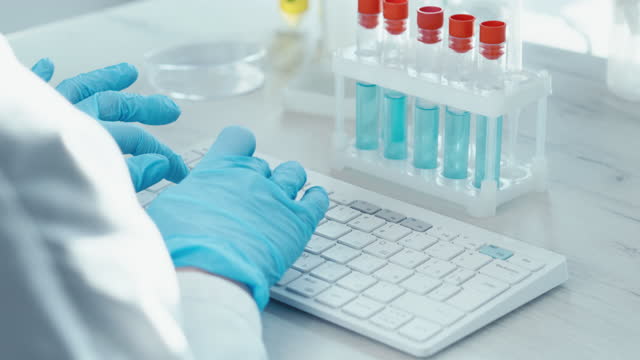Scientist in medical laboratory analyzes medical data and contributes to development science. Doctor types data on keyboard. Computer experiments in laboratory using biotechnology, chemical reactions