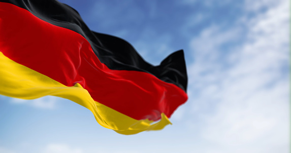 Germany national flag waving in the wind on a clear day. Three horizontal bands of black, red and gold. 3d illustration render. Rippled textile. Selective focus