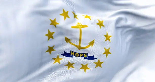 Close-up of the Rhode Island state flag waving. Gold anchor in the center surrounded by thirteen gold stars. 3d illustration render. Close-up. Textured fabric background. Selective focus