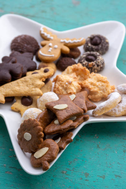 istock Decorated traditional Christmas gingerbreads arranged on white plate in star shape, various xmas shape cookies 1487554367