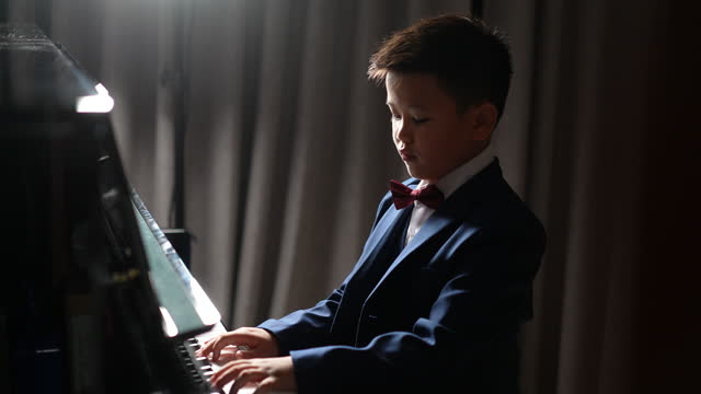 Asian boy practice playing piano at home