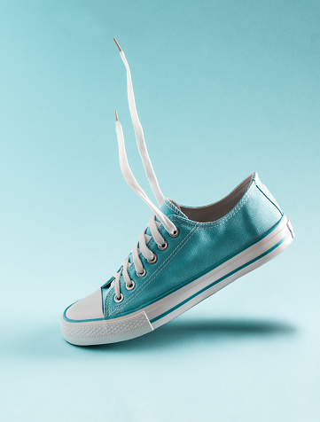 A classic blue sneaker floats in the air on a blue background.