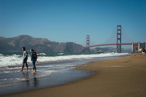 two people wading in ocean near golden gate bridge in san francisco
