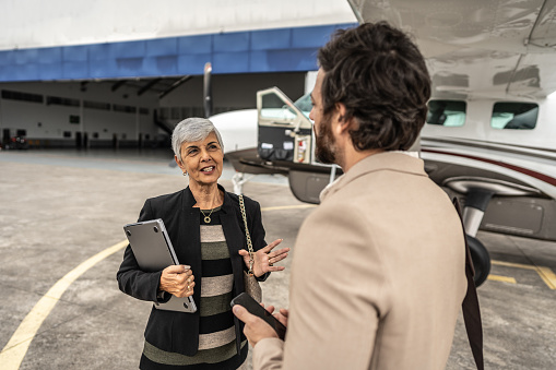 Senior woman talking with her coworker in the airport hangar