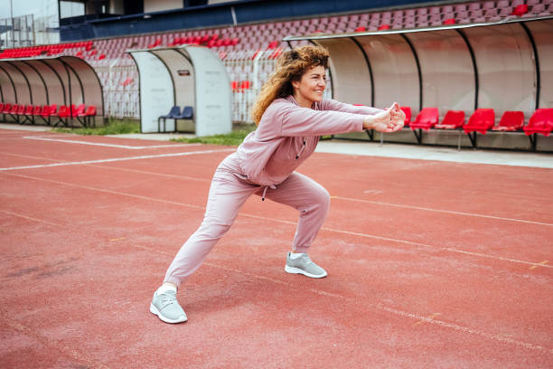 une jeune femme s’étire avant de courir - track and field 30s adult athlete photos et images de collection