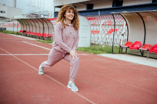 une jeune femme s’étire avant de courir - track and field 30s adult athlete photos et images de collection