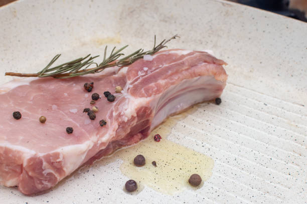Raw pork steak with rosemary and black pepper