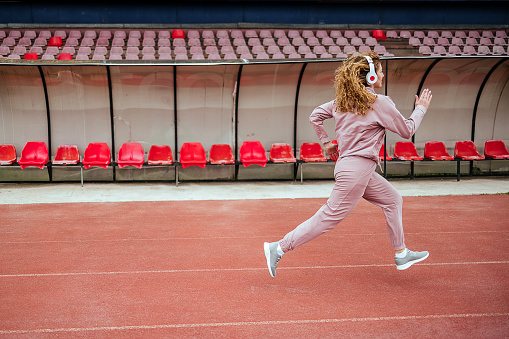 Young woman is running on a track in a stadium