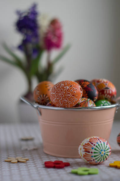 istock Homemade handmade painted Easter eggs in decorative old pink color tin on flowered tablecloth with flowering hyacinth flowers 1487564275