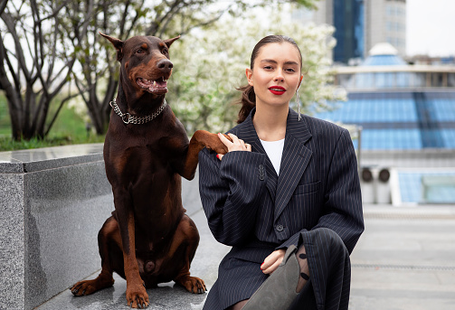 young girl in a suit with a brown doberman on a city street