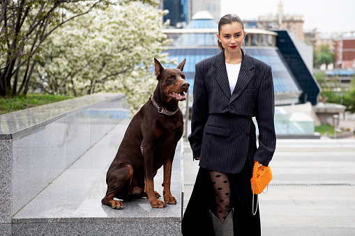 young girl in a suit with a brown doberman on a city street