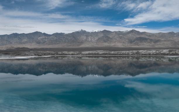 istock a boat floating in water in front of mountains with clouds 1487565669