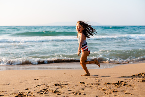 Playful little girl running on the beach