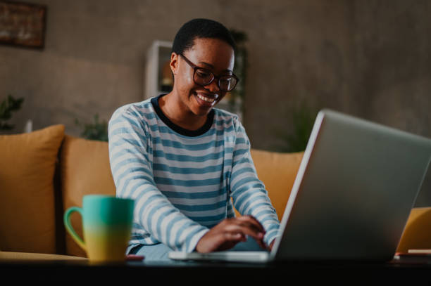 istock African american woman using laptop while sitting on a sofa at home 1487568138