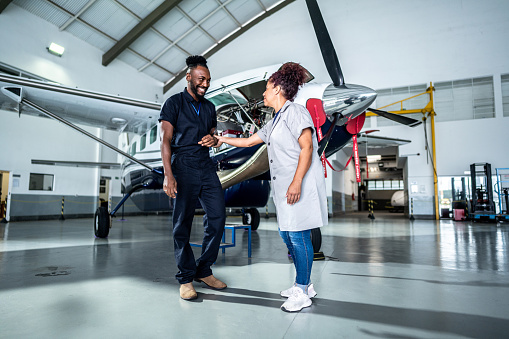 Mature woman inviting her coworker for a dance in the airport hangar