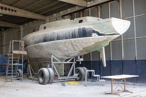 Fiberglass yacht being repaired at a shipyard. Boat restoration